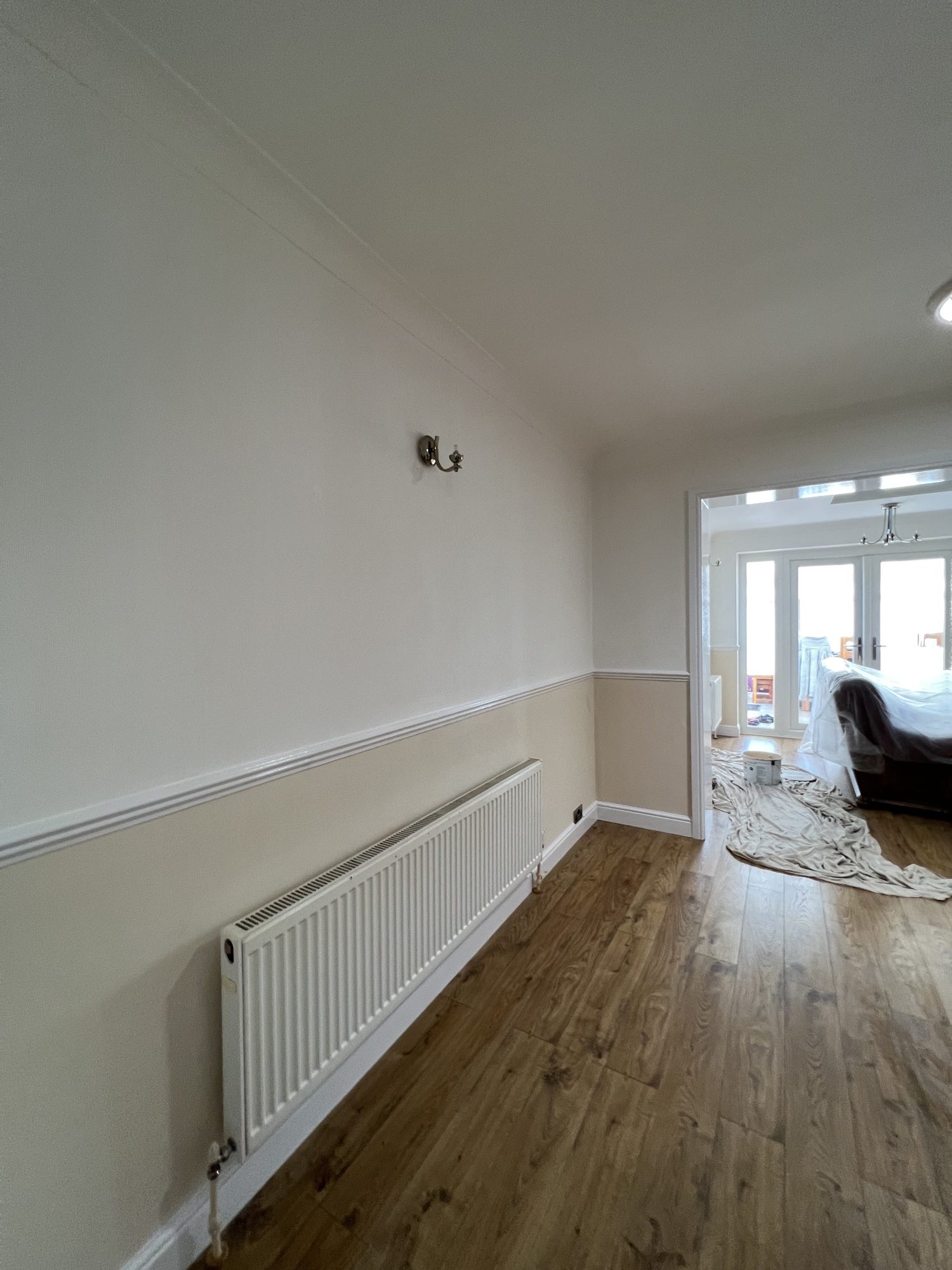 A hallway with a cream and white dado rail above a radiator