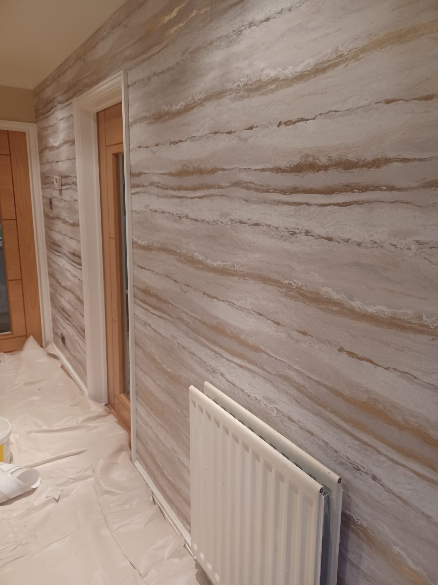 A hallway wall in a marbled brown, gold and white decorative finish